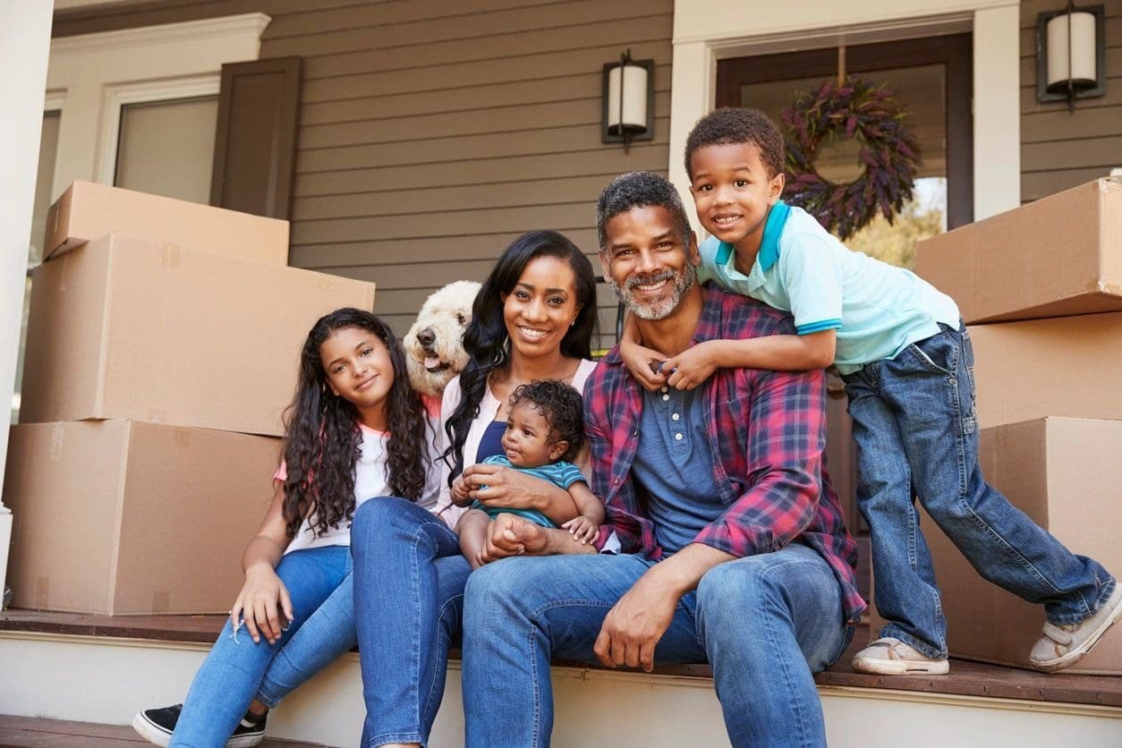 A family sitting on the steps of their home.