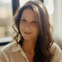 A woman with long hair is smiling for the camera.